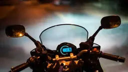 Motorcycle speedometer glowing at night on the handlebars