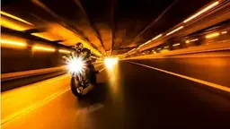 Motorcycle with light trails racing through a tunnel at night